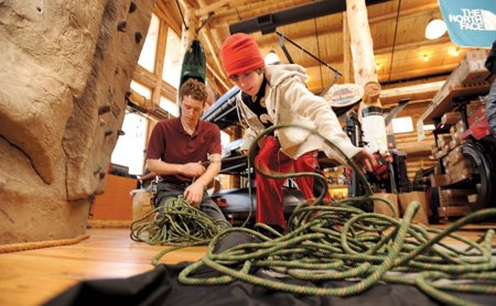 Jackson White, 10, of Springdale, right, helps Cole Fennel, Pack Rat Outdoor Center salesman, untangle climbing rope Jackson purchased Saturday at the longtime Fayetteville business.