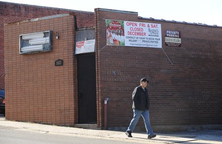 Dell Hall of Fayetteville, whose family owns longtime Fayetteville business World Tresures, walks along Block Avenue Thursday, Dec. 17, 2009, past Maxine's Tap Room which is closed during December. Andrea Foren, owner of the longtime bar, plans to reopen Jan. 8.