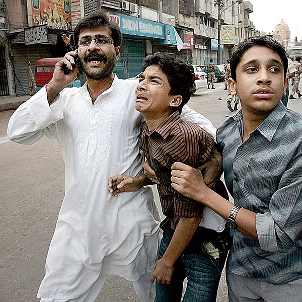  People escort an injured person to an ambulance following a bomb blast in Shiite Muslim procession in Karachi, Pakistan on Monday, Dec. 28, 2009. 