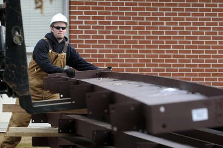 Michael Bisbee, with Multi-Craft Contractors, shifts a section of structural steel as a co-worker uses a loader to stack the pieces Tuesday at Central Junior High School in Springdale. The pieces will be moved by a 60-ton crane for construction of an addition to the school.