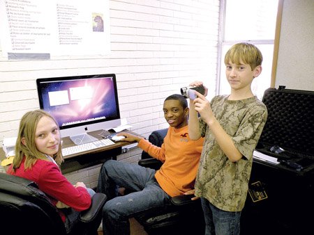 Seventh-grader Austin Montgomery, standing, videotapes Kiersten O’Bryan, left, seventh-grader, and Jared Walker, eighth-grader, as they work on one of the new iMac computers in an EAST — Environmental And Spatial Technology — Lab at Malvern Junior High School. 