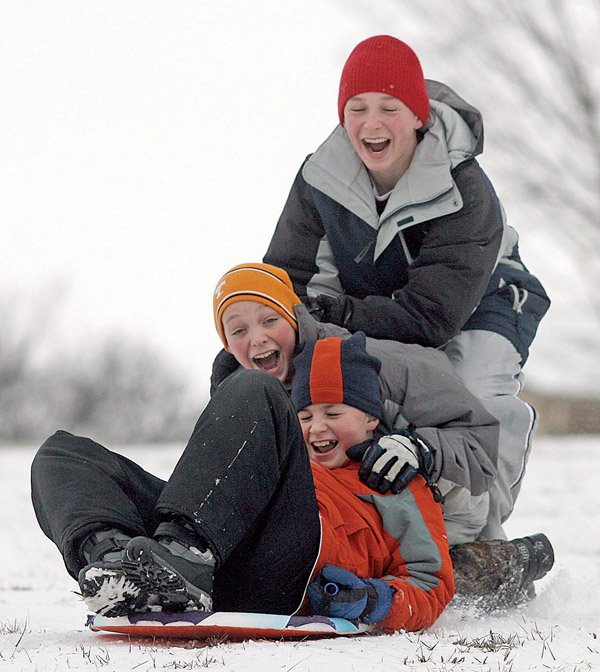 Zac Griffin (from front), 12, Matthew Crenshaw, 12, and his brother Josh Crenshaw, 14, sled down a hill Wednesday in Bentonville. Northwest Arkansas, blanketed by snow earlier in the week, was expected to get another 1 to 3 inches Wednesday night as bitter arctic cold moved into the state.