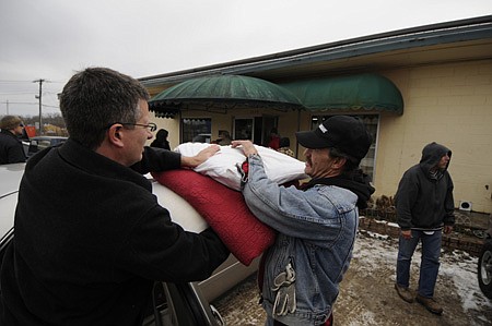 SHELTER FROM THE STORM: Jim Ed Summers, left, hands donated blankets and pillows to Preston Boswell on Wednesday at the Seven Hills Homeless Shelter in Fayetteville. The facility opened overnight Tuesday and Wednesday as a shelter from frigid temperatures. In Fayetteville, the primary shelter is the Salvation Army near 15th Street and South School Avenue followed by Seven Hills, at 1555 W. Martin Luther King Jr. Blvd. The city will open the Yvonne Richardson Center on South Rock Street if the two other sites reach capacity. In Elkins, city officials plan to keep City Hall open overnight today and Friday for anyone needing shelter. Springdale has opened the John Powell Senior Center at Park Street and Grove Avenue as an emergency shelter.

