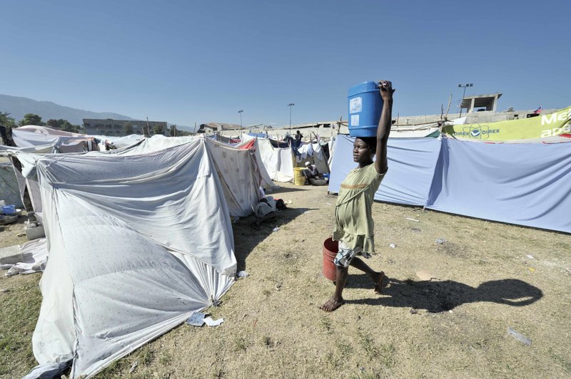 A woman carries water to her temporary shelter in Port-au-Prince, Haiti.( AP Photo/Paul Jeffery, ACT Alliance, ho) 