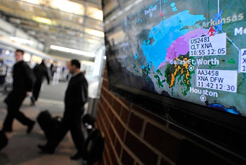An image of the winter storm descending on Northwest Arkansas is pictured on a monitor Thursday, Jan. 28, 2010, as travelers enter the terminal at Northwest Arkansas Regional Airport in Highfill. As of noon only a few flights in and out of XNA had been canceled due to winter weather.