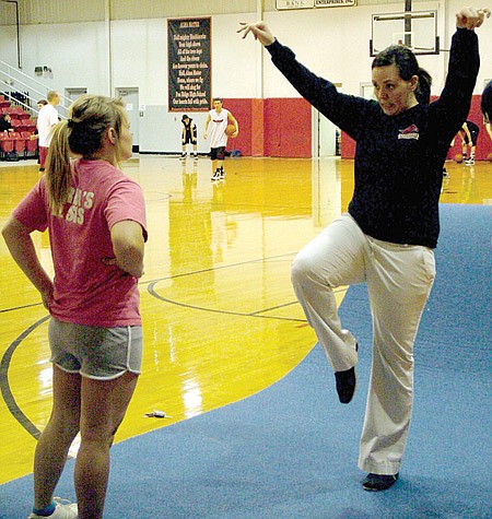 Coach Courtney Hurst, shown here with Lacy King, works with her cheer team continually encouraging them to do their best.
