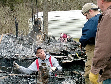 Benton County fire marshal Will Hanna searches for evidence with Sheriff’s investigator Jeremy Felton as they sift through the ashes at the former home of Jeremiah and Samantha Cotton. Watching is Jeremiah’s maternal grandfather, Gary Fletcher, who built the house in 1995.
