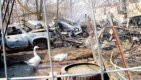 Taking a gander — geese watched as firefighters from six area fire departments extinguished the fire of a garage behind a double-wide trailer in Avoca.