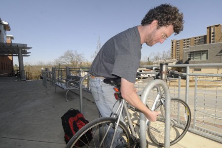 Danial Estes of Fayetteville locks his bicycle Friday at the Fayetteville Public Library. Estes says he always locks his bike after he had one stolen a few years ago.