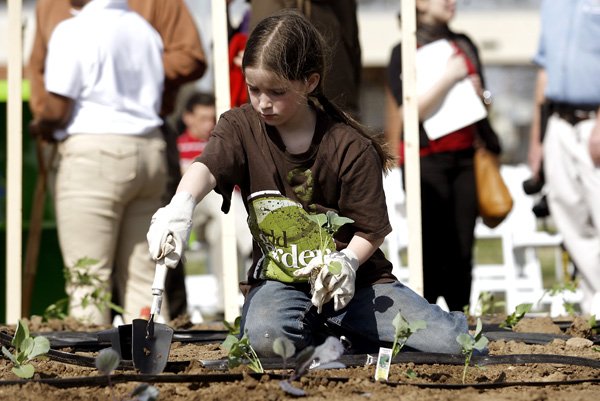 IN THE SWEET SUNSHINE - Peyton Boosey, 10, of Fayetteville plants sweet peppers Thursday in a community garden at the corner of 28th Street and Walton Boulevard in Bentonville. The garden is one of 50 that will be planted across the country.
