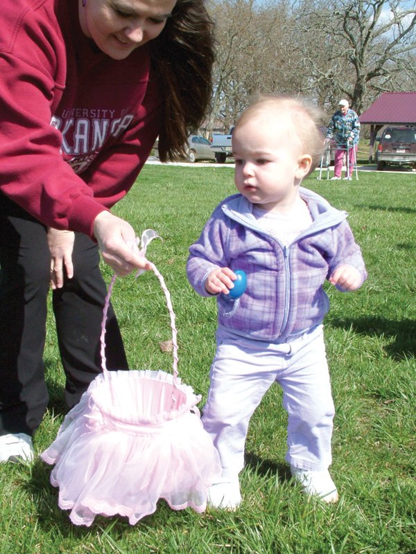 Morgan Ivy, 15 months, hunted Easter eggs at the annual Beta Alpha Sorority Easter Egg Hunt Saturday, March 27, at Pea Ridge City Park assisted by her mother, Jennifery Ivy. She is the daughter of Shannon and Jennifer Ivy. Dorothy Williams, a charter member of Beta Alpha, is in the background. 