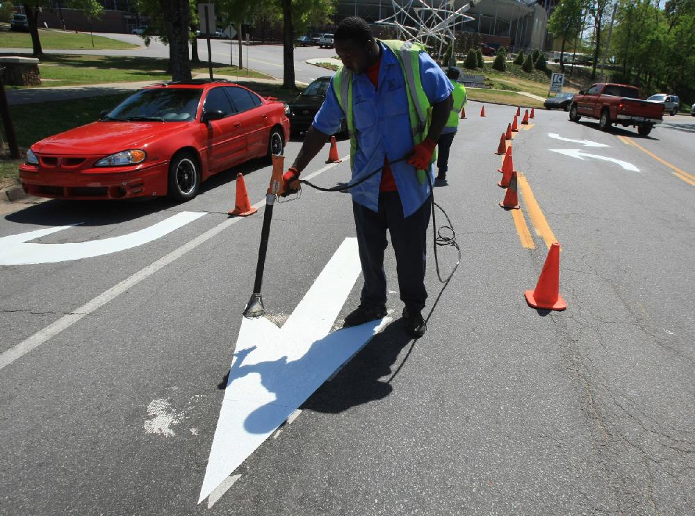 Arkansas Democrat-Gazette STATON BREIDENTHAL --41210-- Little Rock Public Works Department employee Stephen Shelton works Monday afternoon installing new direction arrows in the northbound lanes of Fair Park Blvd. at the Markham Street intersection.