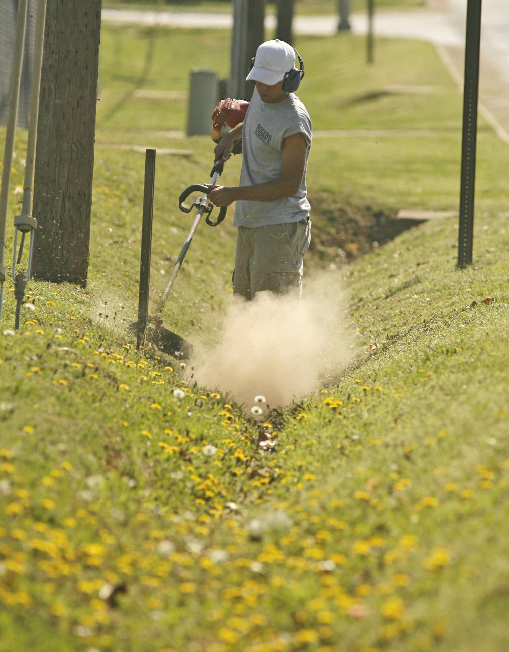 Arkansas Democrat-GazetteBOB COLEMAN--41210--Oscar Cardona of Rogers trims grass and weeds i a drainage ditch along W. Olrich St in Rogers Monday morning. Cardona works with the grounds crew at Heritage Hight School in Rogers.