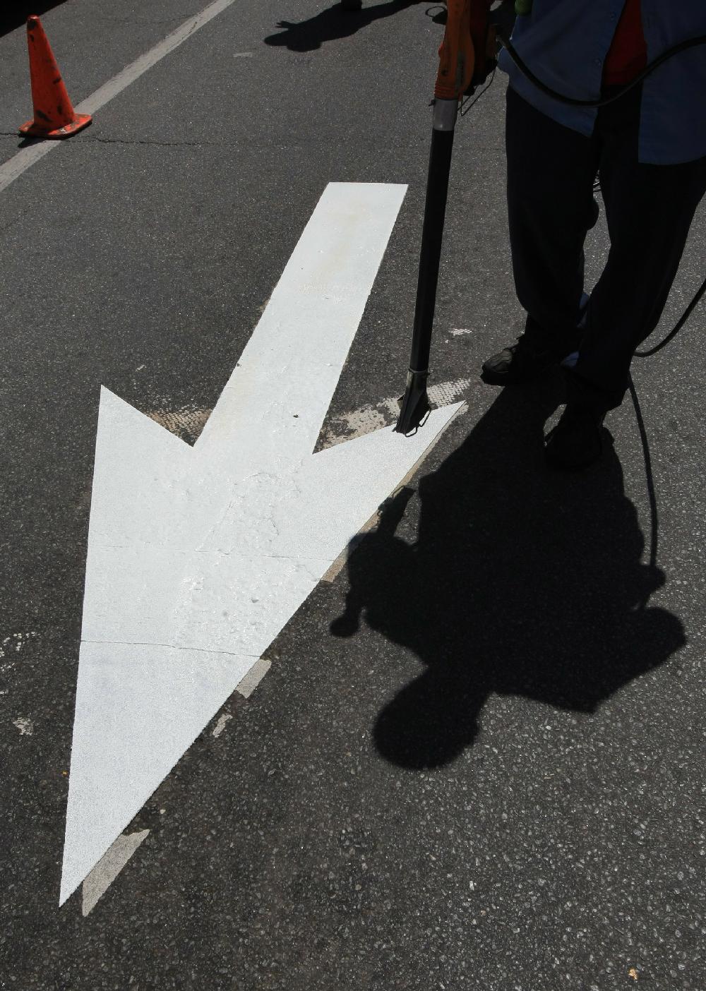 Arkansas Democrat-Gazette STATON BREIDENTHAL --41210-- Little Rock Public Works Department employee Stephen Shelton works Monday afternoon installing new direction arrows in the northbound lanes of Fair Park Blvd. at the Markham Street intersection.