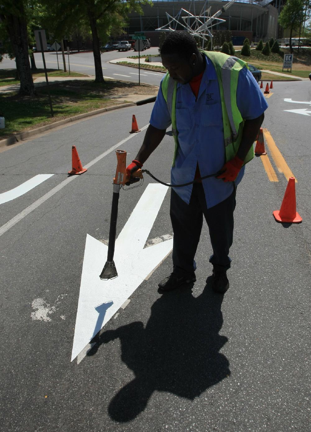 Arkansas Democrat-Gazette STATON BREIDENTHAL --41210-- Little Rock Public Works Department employee Stephen Shelton works Monday afternoon installing new direction arrows in the northbound lanes of Fair Park Blvd. at the Markham Street intersection.