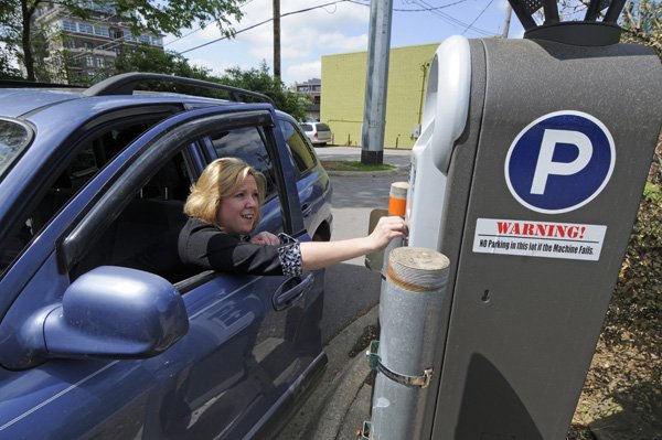 Jamie Daniels of Farmington pays to park in a Fayetteville municipal lot Monday. About 20 of these pay stations would be installed around Dickson Street and downtown if the Fayetteville City Council adopts paid parking proposals for most streets and city-owned lots.