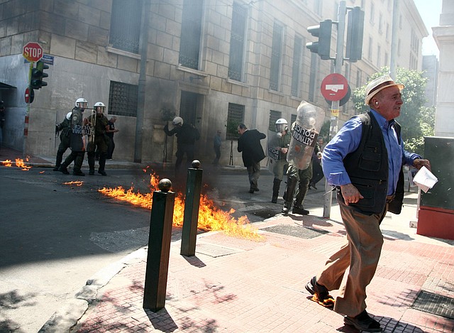 A man with his foot on fire is among riot police and pedestrians trying Saturday to avoid gasoline bombs being thrown by protesters in Athens.