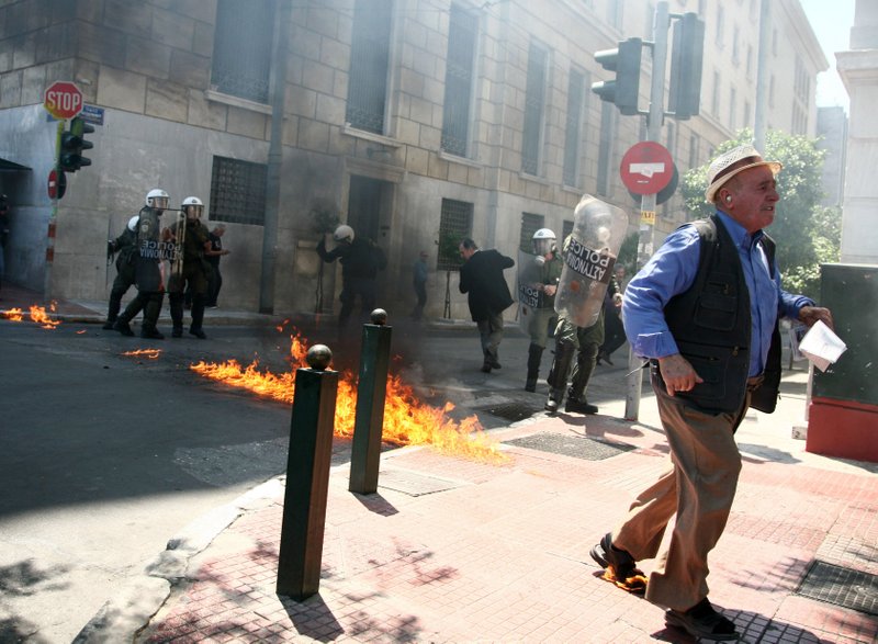 A man with his foot on fire is among riot police and pedestrians trying Saturday to avoid gasoline bombs being thrown by protesters in Athens.