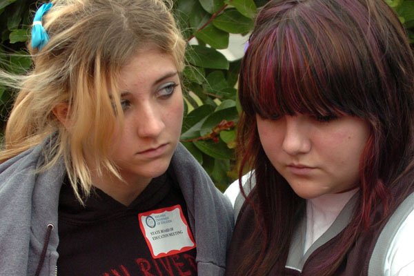 Students of the Twin Rivers School District, ninth-grader Allie Rutledge (left) and 10-grader Kaily Greene wait outside after the Arkansas Department of Education voted Monday to dissolve the district for failing to meet accreditation standards. The students will be assigned to other school districts next school year.