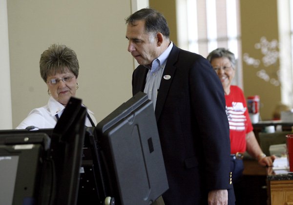 Election official Lora Bradford, left, helps start the electronic voting machine for John Boozman, Republican candidate for Arkansas U.S. Senate, on Tuesday inside the First Church of the Nazarene in Rogers.