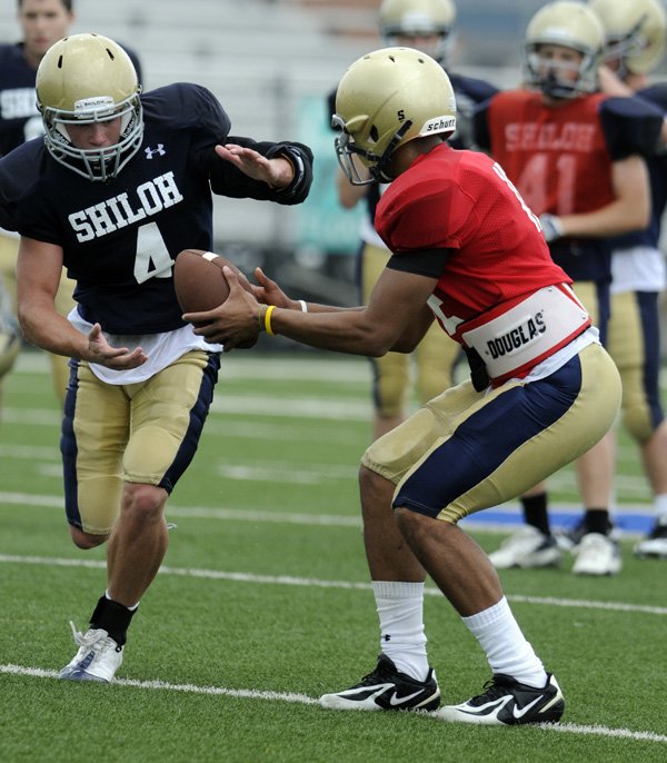 Shiloh Christian quarterback Kiehl Frazier hands off to running back Garrett Harper during practice Tuesday in Champions Stadium in Springdale.