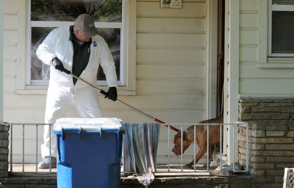 Bill Boyd, animal control officer with the Bentonville Police Department, removes a dog from a home at 408 N.W. Sixth St. in Bentonville on May 27, 2010, as detectives search the home for evidence after discovering a working meth lab in the home. Officers arrested five adults and removed two children from the home after the discovery.