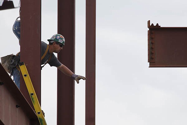 In this April 27, 2010 photo, a construction worker guides a beam into place on a building.