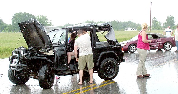 Lending a hand | Karl Schmidt held a towel to a laceration on the head of the driver of the Jeep involved in a two-vehicle accident May 25 at Avoca. Schmidt is a former Pea Ridge police officer and currently works part-time for Little Flock Police. See the related story on page 1A.
