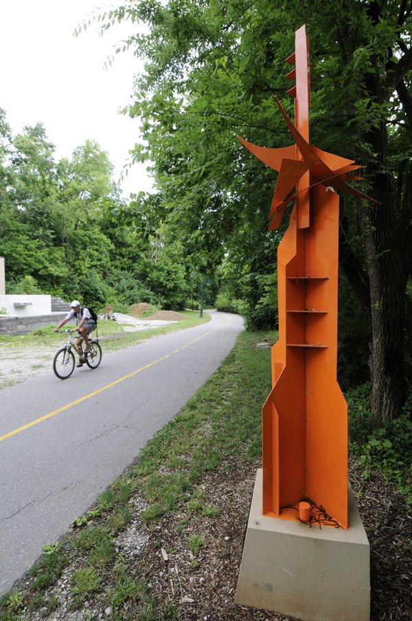 A cyclist rides past the sculpture “city fragments” Monday on the Frisco Trail in Fayetteville. Fayetteville Parks and Recreation officials are planning another public art location at the entrance to the Frisco Trail near Wilson Park.