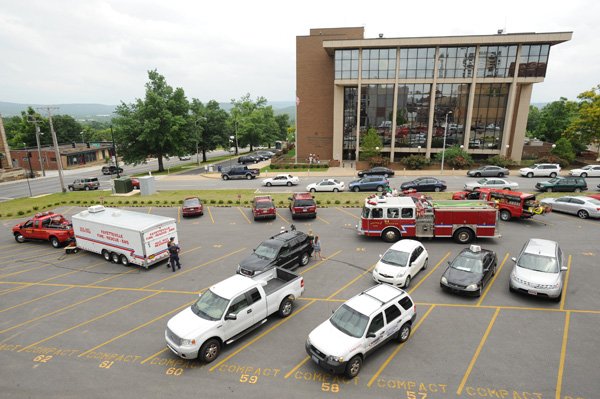 Fayetteville emergency personnel work in a parking lot north of the John Paul Hammerschmidt Federal Building Thursday in Fayetteville after a package from a prisoner containing a white powdery substance was opened inside the building. The facility was evacuated before officials determined the substance did not pose a threat.