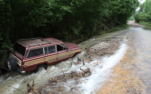 Monty Coffman's Jeep lies in moving waters along highway 240 west of Hopper where their vehicle was washed off the road as Coffman and three others responded to help others early Friday morning. The four held tight to nearby trees for more than an hour before being rescued.
