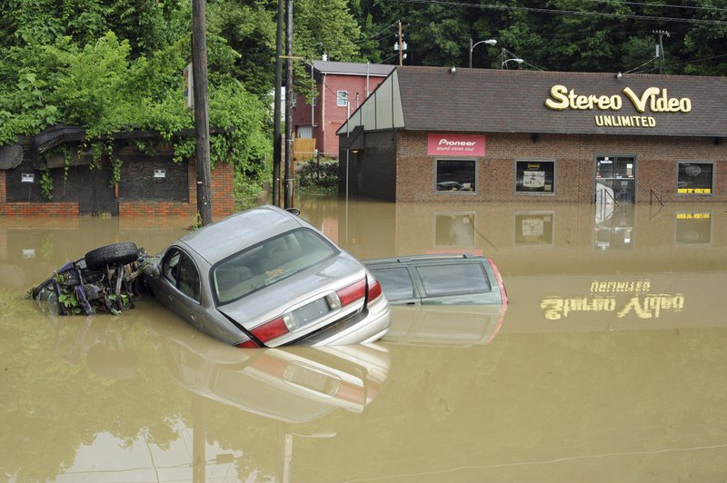 Three automobiles sit on top of each other in water in the road in front of Stereo Video Unlimited in Logan, W.Va, Sunday morning, June 13, 2010, after flash flooding washed through the area. 