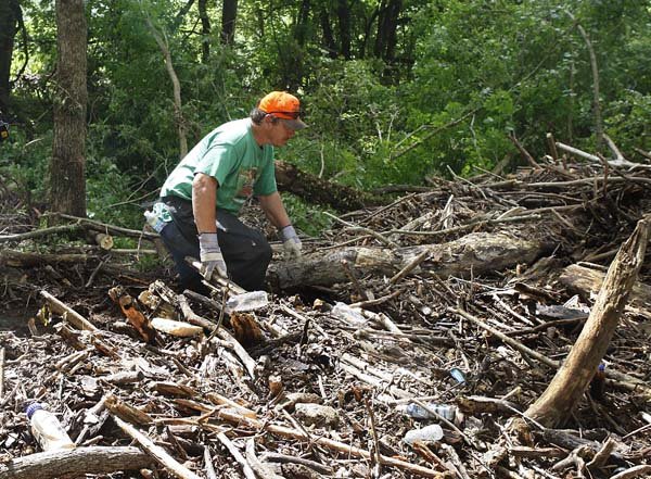 Lenon Main, of Amity, Ark., climbs up on a flood debris pile to search and remove debris, near Langley, Ark., Sunday, June 13, 2010. Search and recovery efforts continue after flooding swept through a nearby campground early Friday, killing at least 18 people. 
