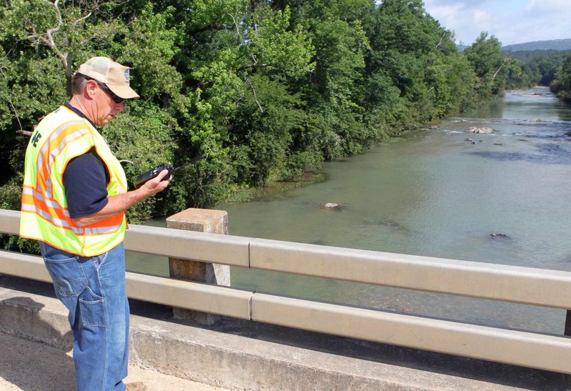 In this Monday, June 14, 2010 photo, Bowie County, Texas, Fire Chief Joel Moss communicates with his search and recovery team headed up river from the Arkansas Highway 84 bridge over the Little Missouri River near Langley, Ark. The grim recovery of bodies after flash flooding tore through a western Arkansas campground was nearing its end Tuesday, as officials awaited DNA tests to confirm that a young girl killed by the rising waters was the final victim. Rescue crews planned a limited search Tuesday of the Albert Pike Recreation Area, where a wall of water came rushing through early Friday after a heavy storm, killing 20 people.