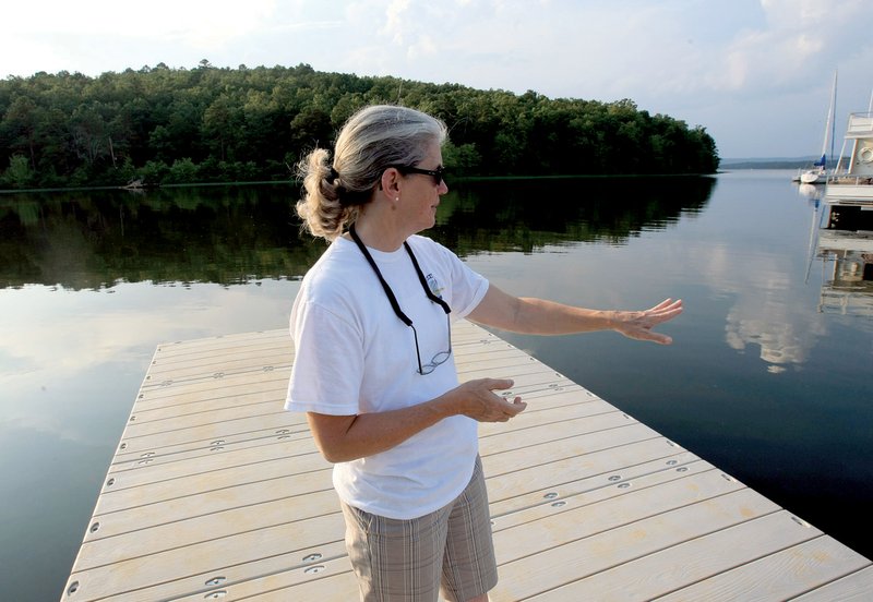 Lynette Watts, Arkansas Boathouse Club board member, stands on the group’s new dock on Lake Maumelle on Wednesday before going out on the lake to map out rowing routes for the club. The group plans to begin rowing on the lake this weekend.
