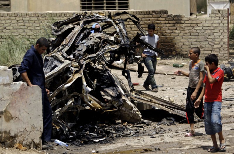 Iraqis stand at the site of a car bomb attack in Baghdad, Iraq, Sunday, June 20, 2010. Twin car bombs exploded Sunday near a major square in Baghdad, killing several people and wounding dozens in the latest attack targeting a high-profile area in the capital.