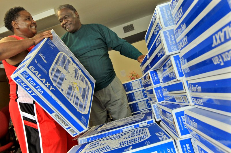 Rev. Hezikiah Stewart, center, gives out fans to Donna Twiggs and other community members who don't have access to air conditioning during the Watershed's annual Beat the Heat program. Entergy Arkansas donated 101 fans.