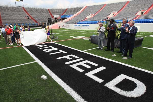 Cheerleaders from Mount St. Mary and Catholic High School uncover a logo Wednesday at War Memorial Stadium in Little Rock after an announcement naming the playing surface the AT&T Field. Announcing the sponsorship were (background left to right) Ed Drilling, AT&T Arkansas president; Terry Williams, Arkansas Veterans Commission chairman; Steve Gray, AT&T vice president and general manager; and Gary Smith, War Memorial Stadium Commission chairman.