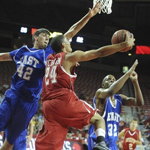 West team member Taylor Cochran (24) tries to split East defenders Spencer Caraway (42) and Michael Perkins (right) as he drives to the basket Thursday night at Walton Arena in Fayetteville