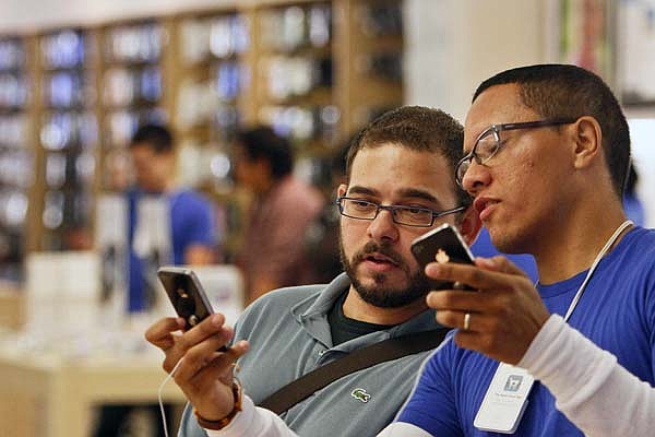  An Apple employee shows Duane Davis (left) the new features of his Apple iPhone 4 on Thursday at the Memorial City Mall Apple Store in Houston during the first day of sales.