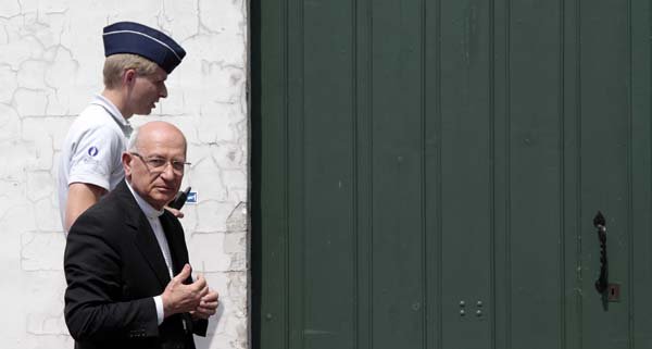 Archbishop Giacinto Berloco, the papal nuncio to Belgium and Luxembourg, walks with a police officer Thursday at the Archdiocese of Mechelen north of Brussels.