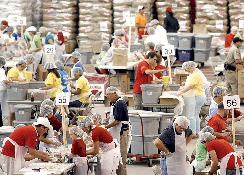 Volunteers diligently fill bags with food on Saturday inside the Randal Tyson Track Center in Fayetteville during the Razorback Relief Operation Haiti.