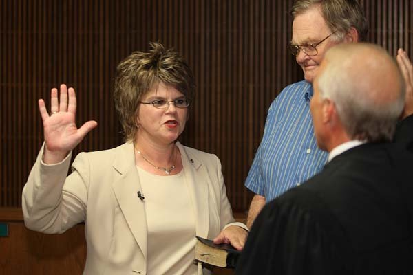   Virginia Hillman, newly elected Sherwood Mayor, takes the oath of office administered by Judge Milas "Butch" Hale III in the Sherwood Council Chambers Wednesday. Hillman's father Harold Fortson, of Jacksonville, held the Bible for her.