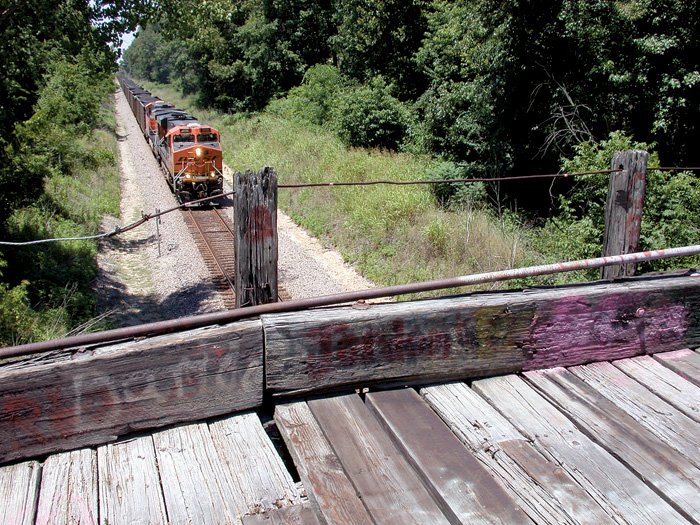 A Burlington Northern Santa Fe train passes underneath a closed wooden bridge near Bono.