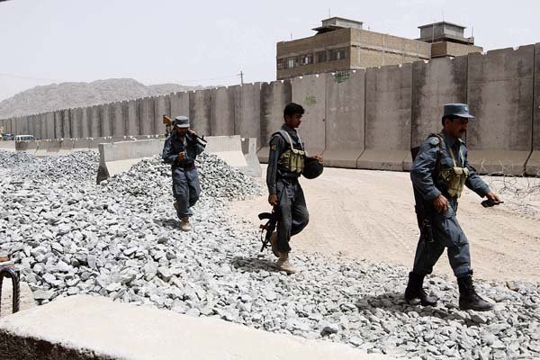 Afghan police patrol their base in Kandahar on Wednesday after an overnight attack that officials said killed three Americans, an Afghan policeman and five civilians.