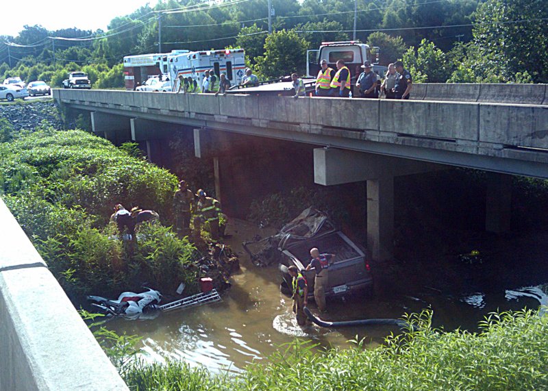Crews climb down to the truck that fell into a creek on the Interstate 30 frontage road on Friday morning.