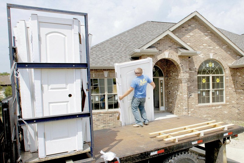 Construction worker Brian Stocks unloads doors for a house under construction this month in Springfield, Ill.