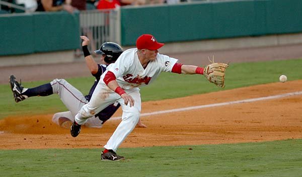 Ryan Mount of the Arkansas Travelers makes an attempt at a catch while Northwest Arkansas’ Ben Theriot slides safely into third base during Tuesday night’s game at Dickey-Stephens Park in North Little Rock. The Naturals won 5-0.