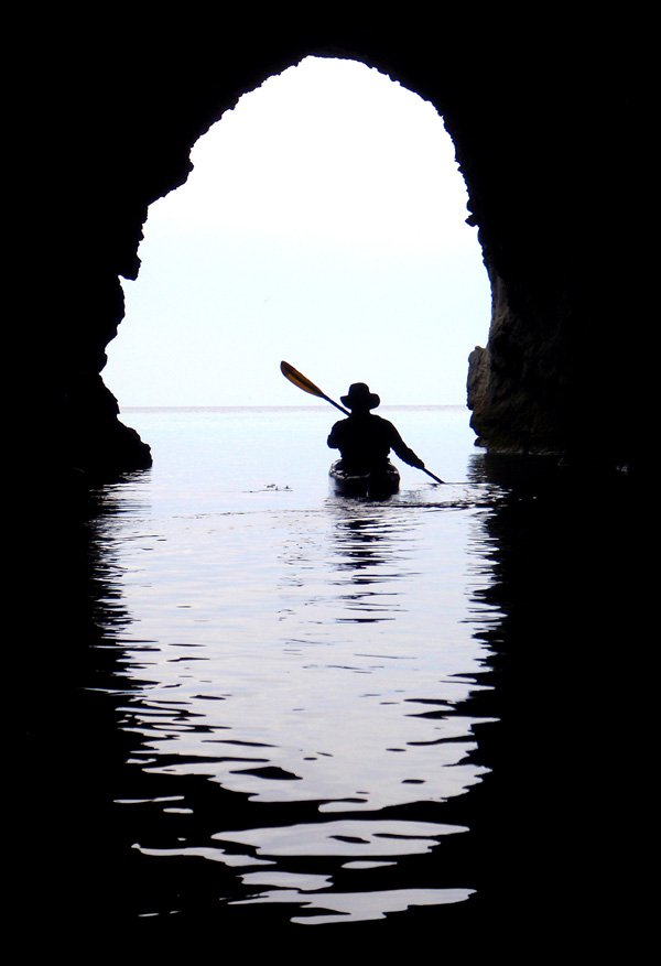 Kayak guide Rod Feldtmann paddles back into the light after exploring a cave on the north coast of Milos, Greece, on April 24. The sea caves that dot most of the coast of Milos help make the island a world class warm water paddling destination.