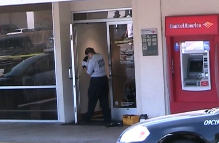 A crime scene officer dusts for prints at a Bank of America robbed at gunpoint Wednesday.